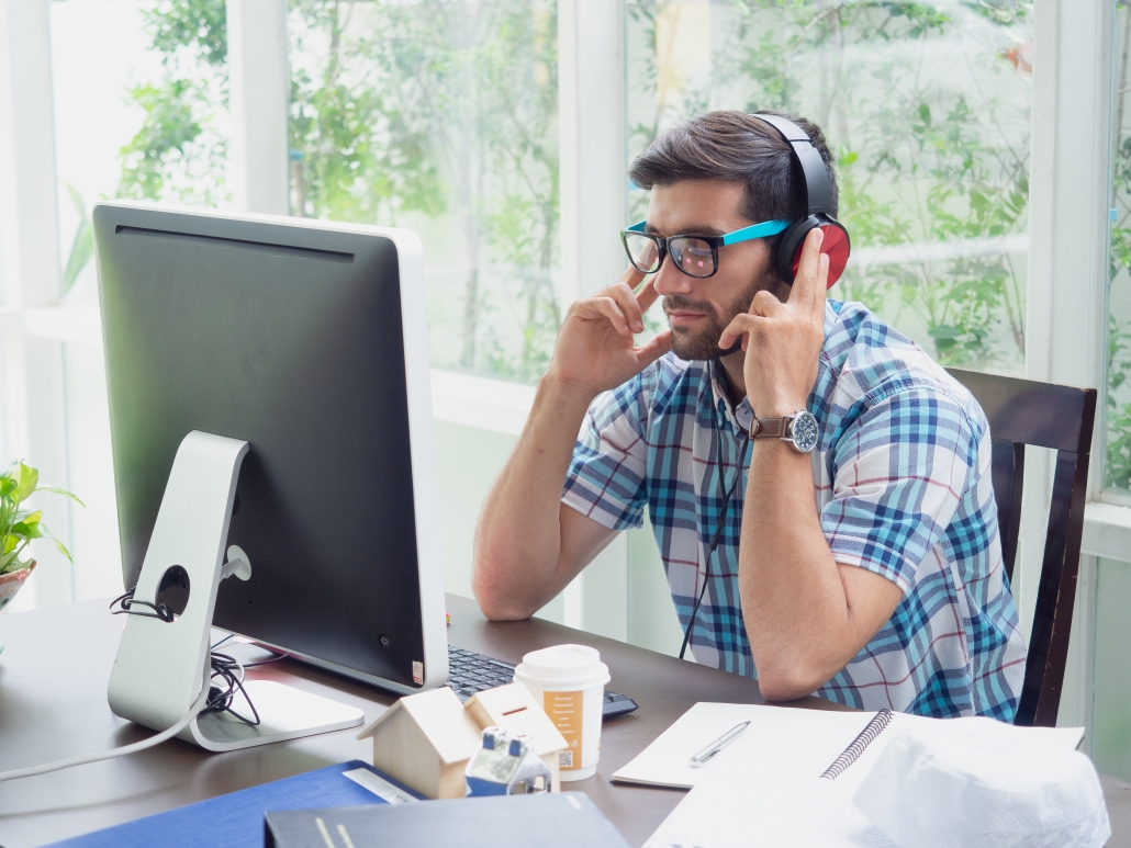 Young man relaxing at home infront of PC with headphones on